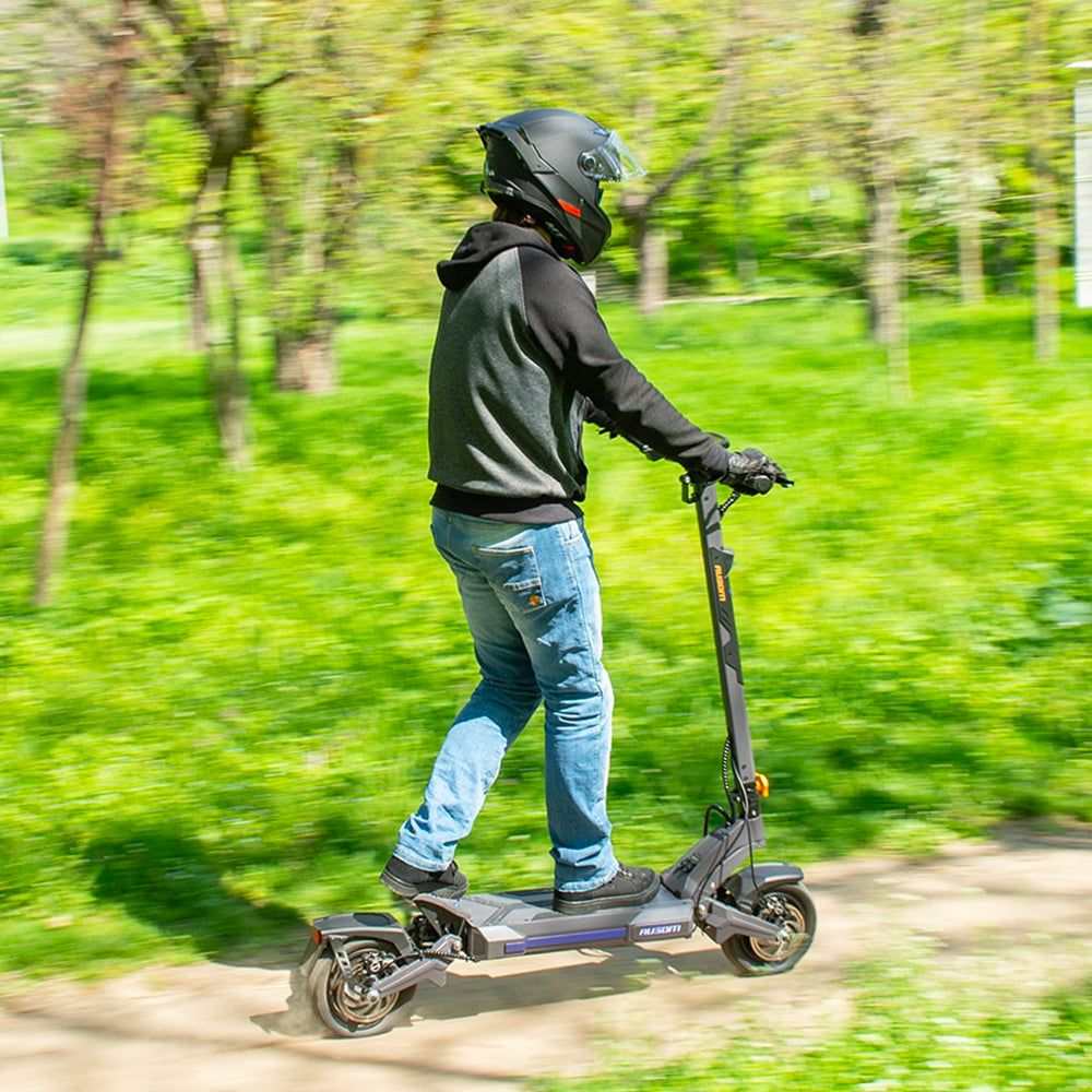 Man riding Ausom DT2 Pro electric scooter on a green trail wearing helmet and casual clothes